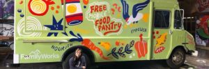 Artist Stevie Shao, kneeling in front of the freshly painted Mobile Food Pantry truck