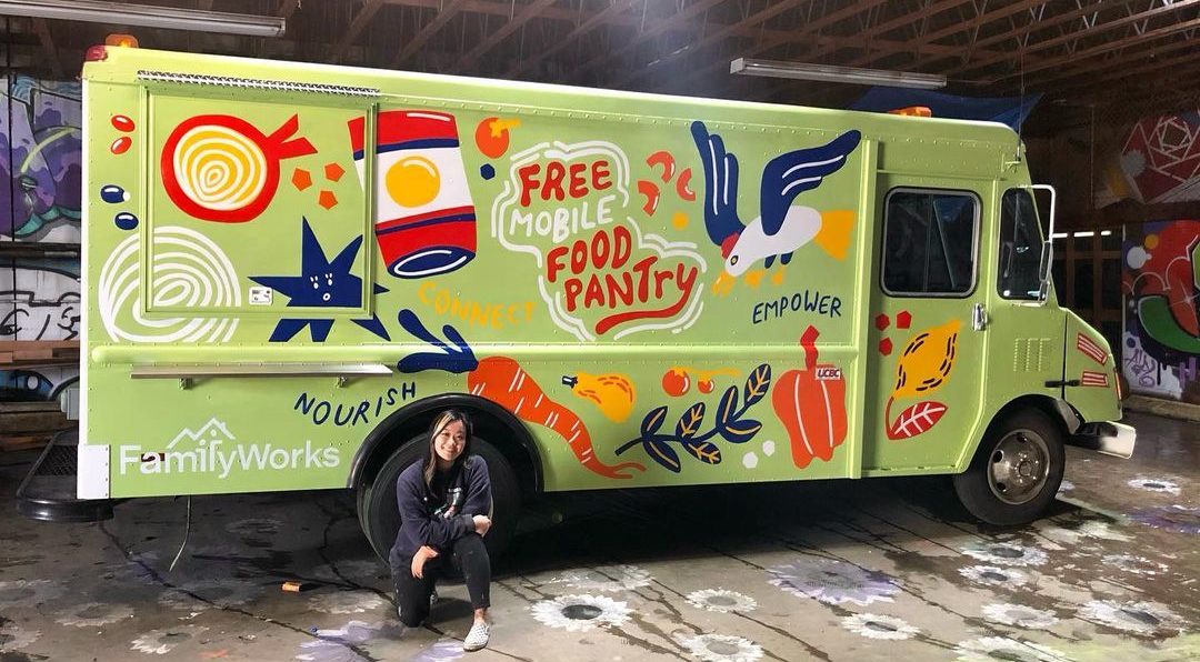 Artist Stevie Shao, kneeling in front of the freshly painted Mobile Food Pantry truck