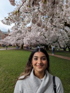 FamilyWorks' MSW Intern Shruti Niravane (she/her) poses under a blooming cherry blossom tree at the University of Washington.